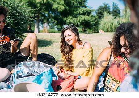 Stock Image - Group of friends relaxing at picnic in park. Fotosearch