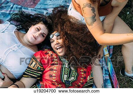 Stock Image - Group of friends relaxing at picnic in park. Fotosearch