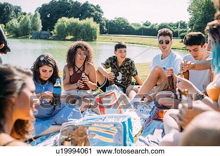 Stock Image - Group of friends relaxing at picnic in park. Fotosearch