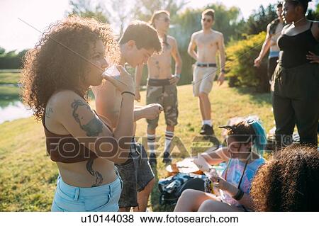 Stock Photo - Group of friends relaxing at picnic in park. Fotosearch