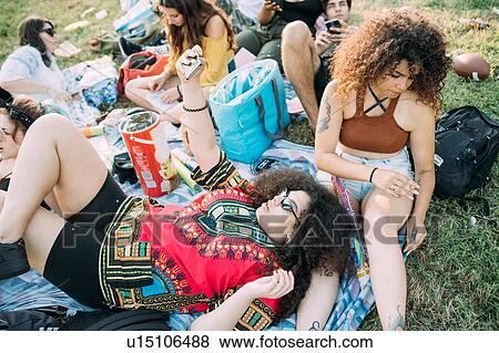 Stock Photo - Group of friends relaxing at picnic in park. Fotosearch