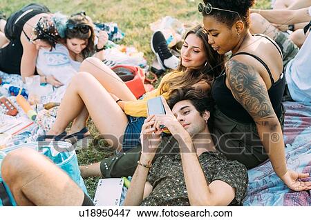 Stock Photo - Group of friends relaxing at picnic in park. Fotosearch