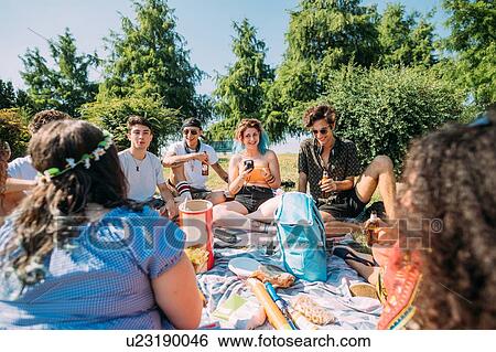 Stock Photograph - Group of friends relaxing at picnic in park. Fotosearch