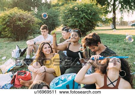 Group of friends relaxing, blowing bubbles at picnic in park View Large Photo Image Stock Image - Group of friends relaxing, blowing bubbles at picnic in park. Fotosearch