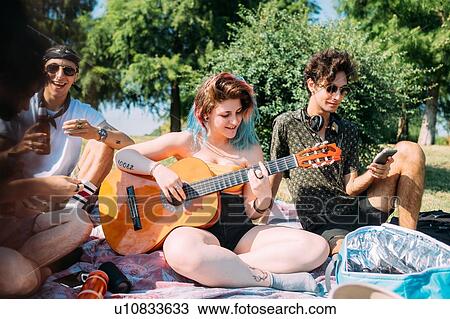Group of friends relaxing, playing guitar at picnic in park View Large Photo Image Stock Image - Group of friends relaxing, playing guitar at picnic in park. Fotosearch