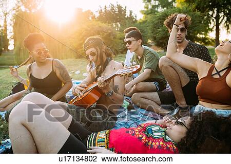 Group of friends relaxing, playing guitar at picnic in park View Large Photo Image Stock Image - Group of friends relaxing, playing guitar at picnic in park. Fotosearch