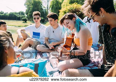 Group of friends relaxing, playing guitar at picnic in park View Large Photo Image Stock Image - Group of friends relaxing, playing guitar at picnic in park. Fotosearch