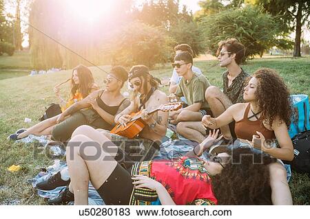 Group of friends relaxing, playing guitar at picnic in park View Large Photo Image Stock Image - Group of friends relaxing, playing guitar at picnic in park. Fotosearch