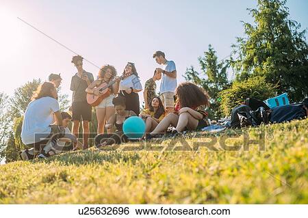 Group of friends relaxing, playing guitar at picnic in park View Large Photo Image Stock Photograph - Group of friends relaxing, playing guitar at picnic in park. Fotosearch