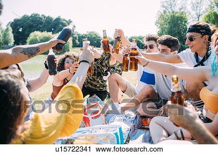 Group of friends relaxing, toasting soft drinks at picnic in park View Large Photo Image Stock Image - Group of friends relaxing, toasting soft drinks at picnic in park. Fotosearch