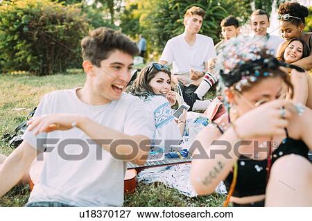 Group of friends watching man playing with confetti at picnic in park View Large Photo Image Stock Photo - Group of friends watching man playing with confetti at picnic in park. Fotosearch