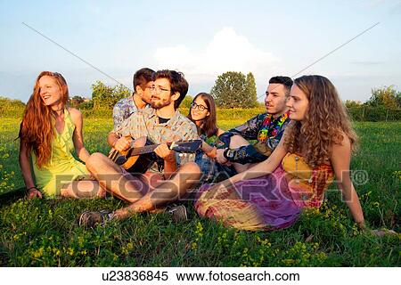 Group of young adults sitting in field listening to acoustic guitar View Large Photo Image Stock Photography - Group of young adults sitting in field listening to acoustic guitar. Fotosearch