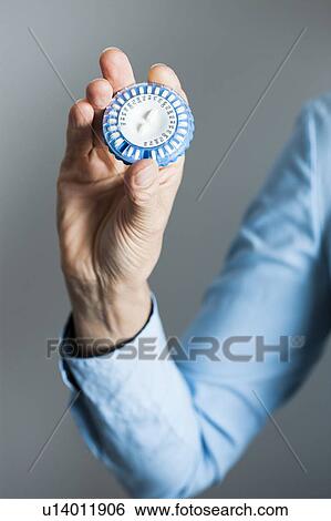 Stock Photograph - Hand holding hormone replacement therapy (HRT) pills. HRT pills are synthetic hormones used to treat menopausal women. They counteract the hormone deficiency that occurs at menopause.. Fotosearch