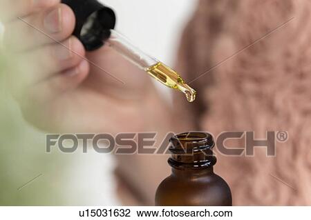 Stock Image - Hand of woman holding pipette of beauty oil. Fotosearch