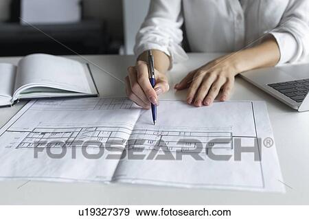 Stock Photo - Hands of businesswoman working on blueprint. Fotosearch