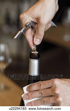 Stock Image - Hands of man opening bottle of wine. Fotosearch