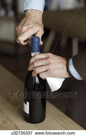 Stock Photo - Hands of man opening bottle of wine. Fotosearch