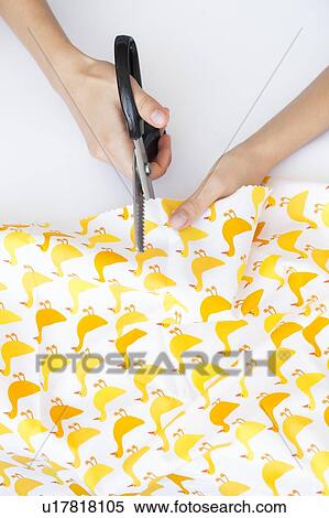 Stock Photography - Hands of woman cutting fabric with duck print. Fotosearch