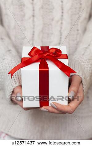 Stock Photo - Hands of woman holding Christmas present with candy cane. Fotosearch