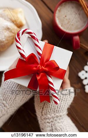 Hands of woman holding Christmas present with candy cane View Large Photo Image Stock Photo - Hands of woman holding Christmas present with candy cane. Fotosearch