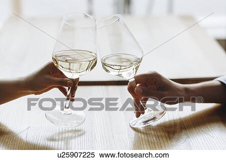 Stock Photography - Hands of women toasting with glasses of white wine. Fotosearch