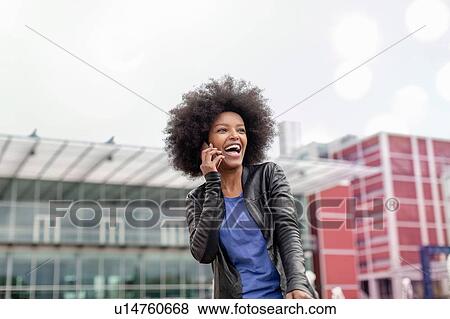 Happy young woman with afro hair in city, laughing and making smartphone call View Large Photo Image Stock Photo - Happy young woman with afro hair in city, laughing and making smartphone call. Fotosearch