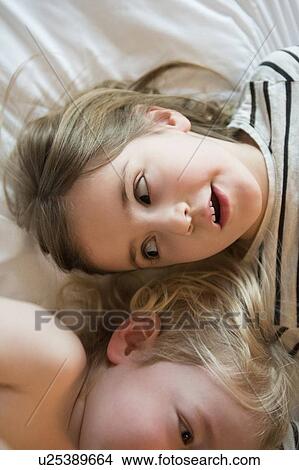 Picture - High angle of children lying on bed. Fotosearch