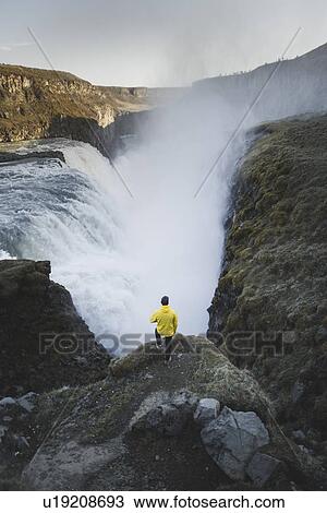 Stock Image - Hiker by Gullfoss waterfall in Iceland. Fotosearch