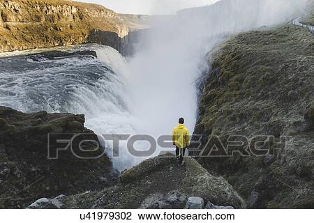 Stock Image - Hiker by Gullfoss waterfall in Iceland. Fotosearch