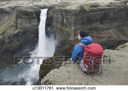 Stock Image - Hiker with backpack on cliff by Haifoss waterfall in Iceland. Fotosearch
