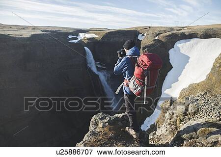 Hiker with backpack on cliff by Haifoss waterfall in Iceland View Large Photo Image Stock Photo - Hiker with backpack on cliff by Haifoss waterfall in Iceland. Fotosearch