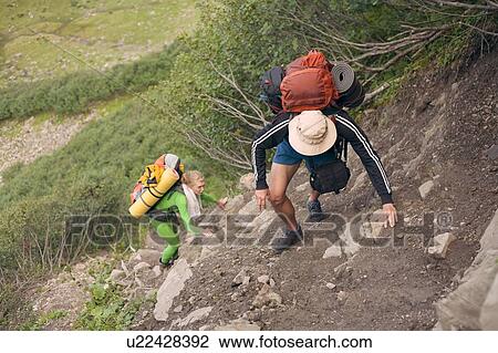 Stock Image - Hiking couple climbing hill. Fotosearch