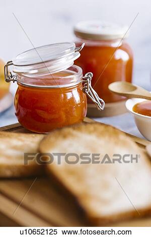 Stock Photography - Jars of apricot jam by toast. Fotosearch