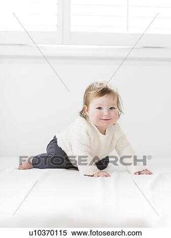 Stock Photography - Kneeling baby girl under window. Fotosearch