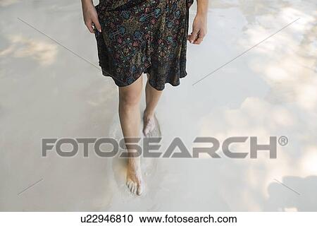 Stock Image - Legs of woman walking on beach. Fotosearch