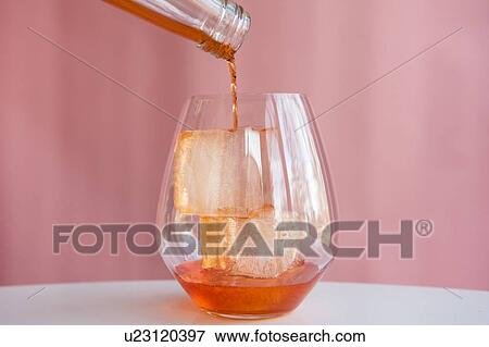 Liquor being poured into glass with ice cubes View Large Photo Image Stock Photo - Liquor being poured into glass with ice cubes. Fotosearch
