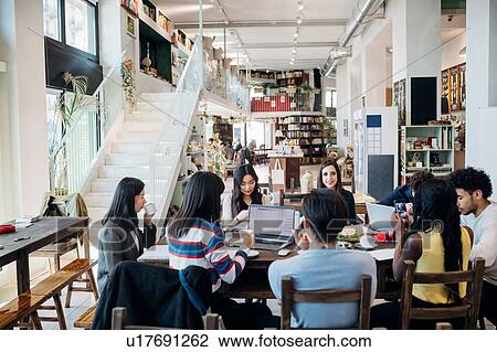 Stock Image - Male and female business team meeting while having working lunch at cafe table. Fotosearch