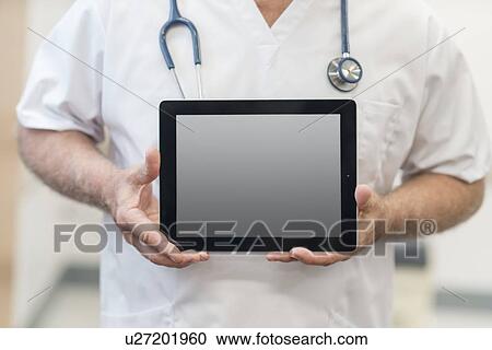 Stock Image - Male doctor holding digital tablet, close up.. Fotosearch