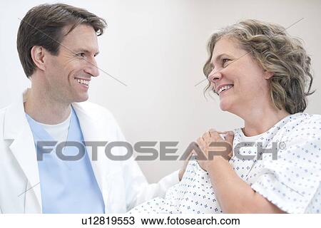 Male doctor smiling at mature female patient. View Large Photo Image Stock Image - Male doctor smiling at mature female patient.. Fotosearch