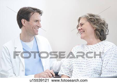 Stock Image - Male doctor smiling at mature female patient.. Fotosearch