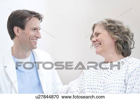 Male doctor smiling at mature female patient. View Large Photo Image Stock Image - Male doctor smiling at mature female patient.. Fotosearch