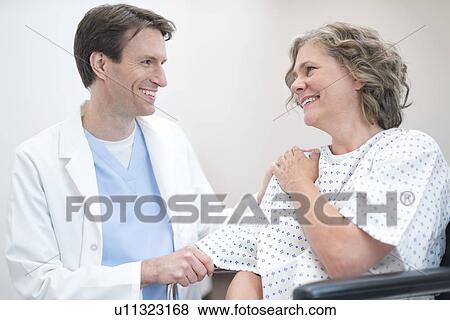 Male doctor smiling at mature female patient. View Large Photo Image Stock Photo - Male doctor smiling at mature female patient.. Fotosearch
