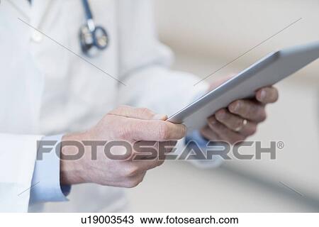 Stock Image - Male doctor using digital tablet.. Fotosearch