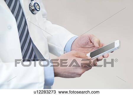 Stock Image - Male doctor using smartphone.. Fotosearch