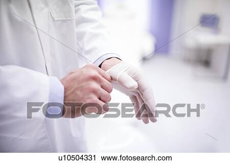 Stock Image - Male doctor wearing surgical glove.. Fotosearch