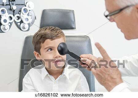 Male optician testing boy's eyesight. View Large Photo Image Stock Image - Male optician testing boy's eyesight.. Fotosearch