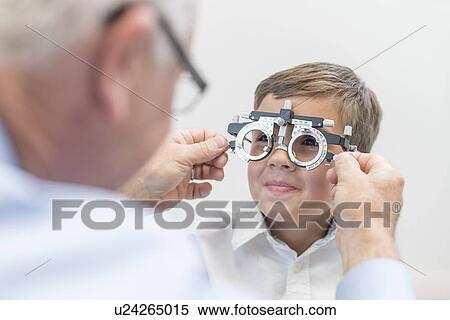 Stock Photography - Male optician testing boy's eyesight.. Fotosearch