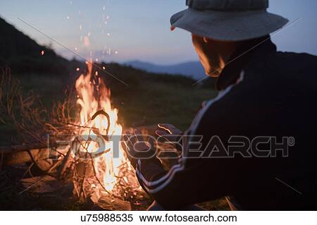 Man crouching by campfire View Large Photo Image Stock Photography - Man crouching by campfire. Fotosearch