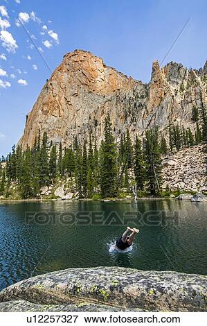 Stock Photo - Man diving into lake by mountain in Stanley, Idaho, USA. Fotosearch