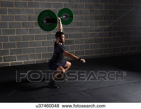 Man doing squats, lifting barbell in gym View Large Photo Image Stock Photo - Man doing squats, lifting barbell in gym. Fotosearch